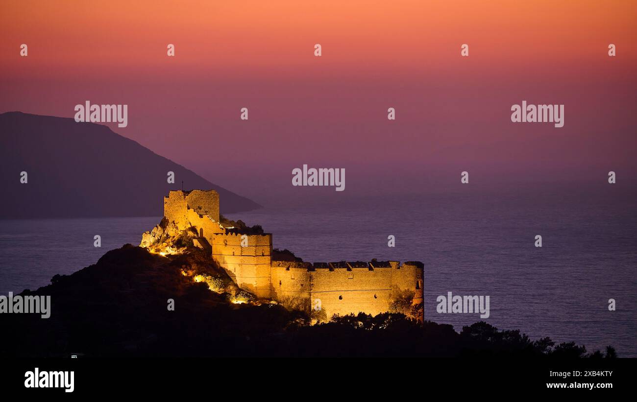 Vista delle rovine illuminate del castello al crepuscolo, circondato dal mare e dalle montagne sotto un cielo colorato, il castello di Kritinia, il castello di San Giovanni e Kritinia Foto Stock