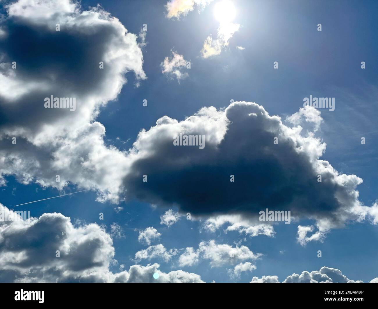 Nuvole scure davanti a Stratocumulus in retroilluminazione sullo sfondo nuvole a grappolo Altocumulus di fronte al cielo blu, internazionale Foto Stock