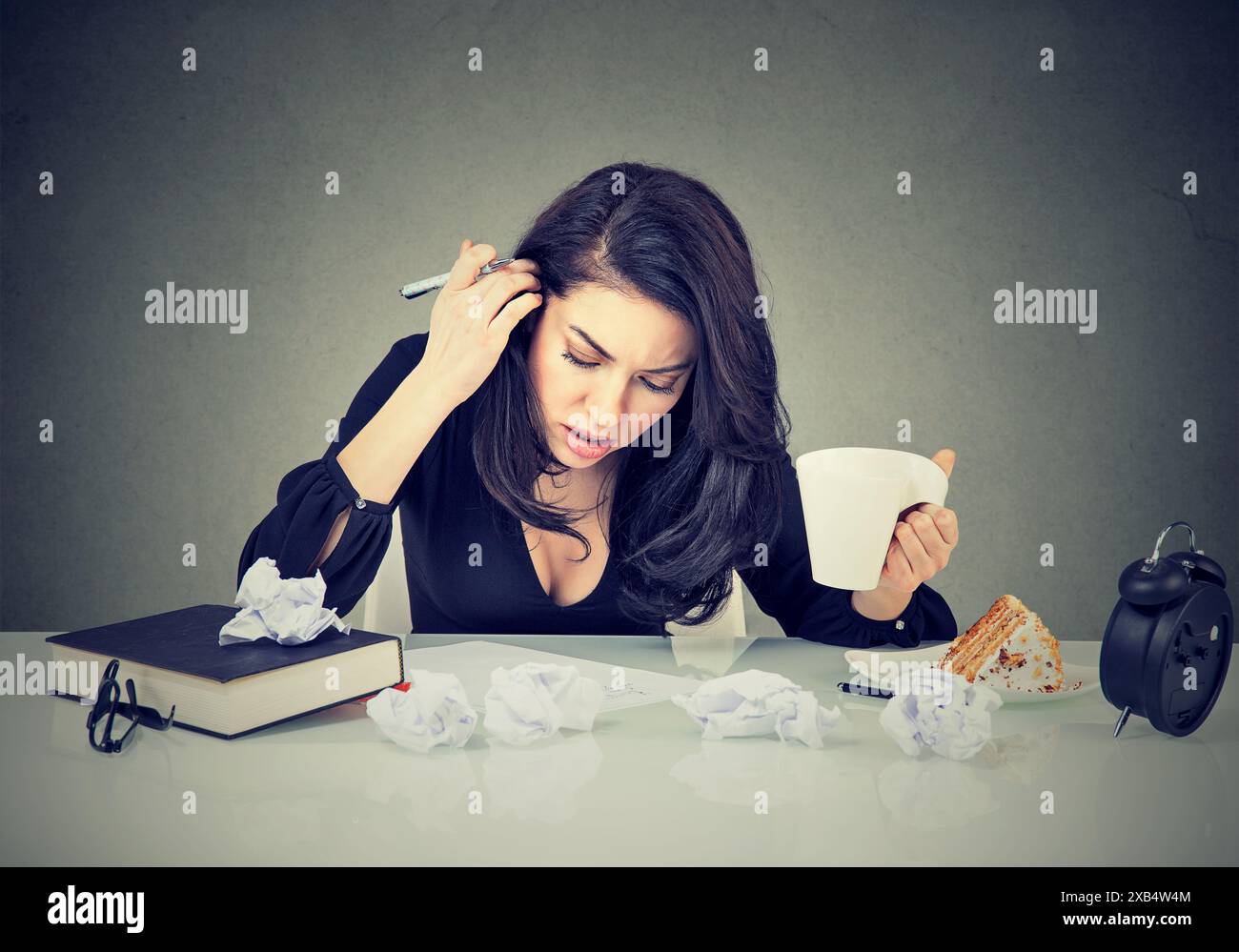 Disperazione e giovane donna molto impegnata che lavora in ufficio su una scrivania disordinata Foto Stock