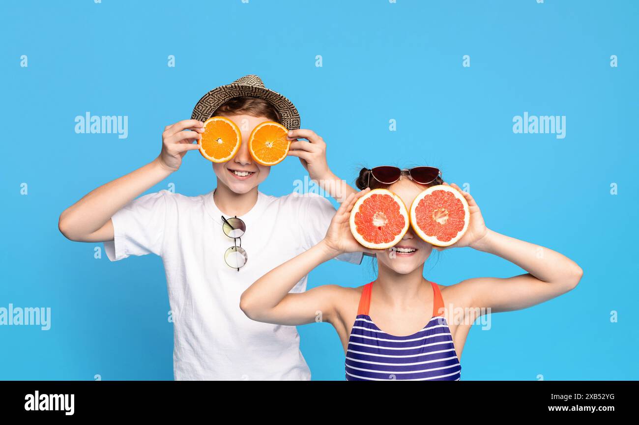 Due bambini che tengono fette di frutta sugli occhi contro il blu Foto Stock