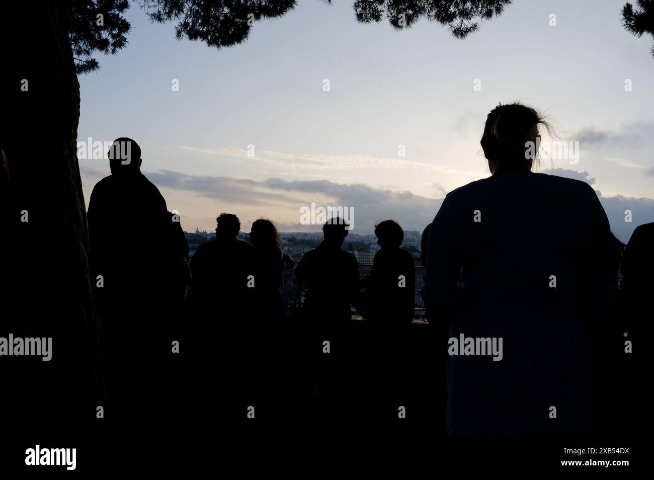Le persone si riuniscono durante i popolari festeggiamenti dei santi a miradouro da graa, con la vista del tramonto della città contro il cielo serale Foto Stock