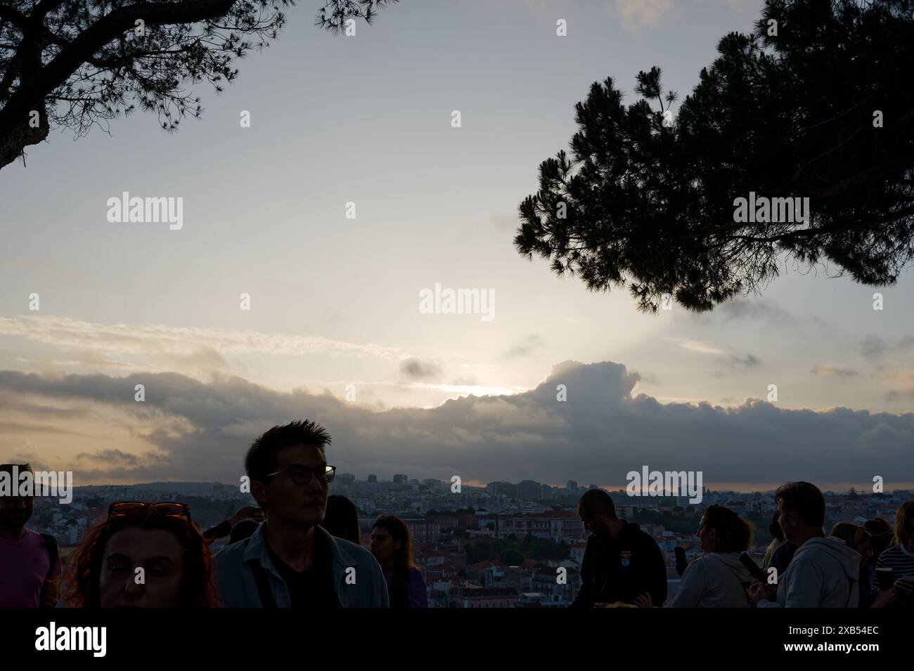 Le persone si riuniscono durante i popolari festeggiamenti dei santi a miradouro da graa, con la vista del tramonto della città contro il cielo serale Foto Stock
