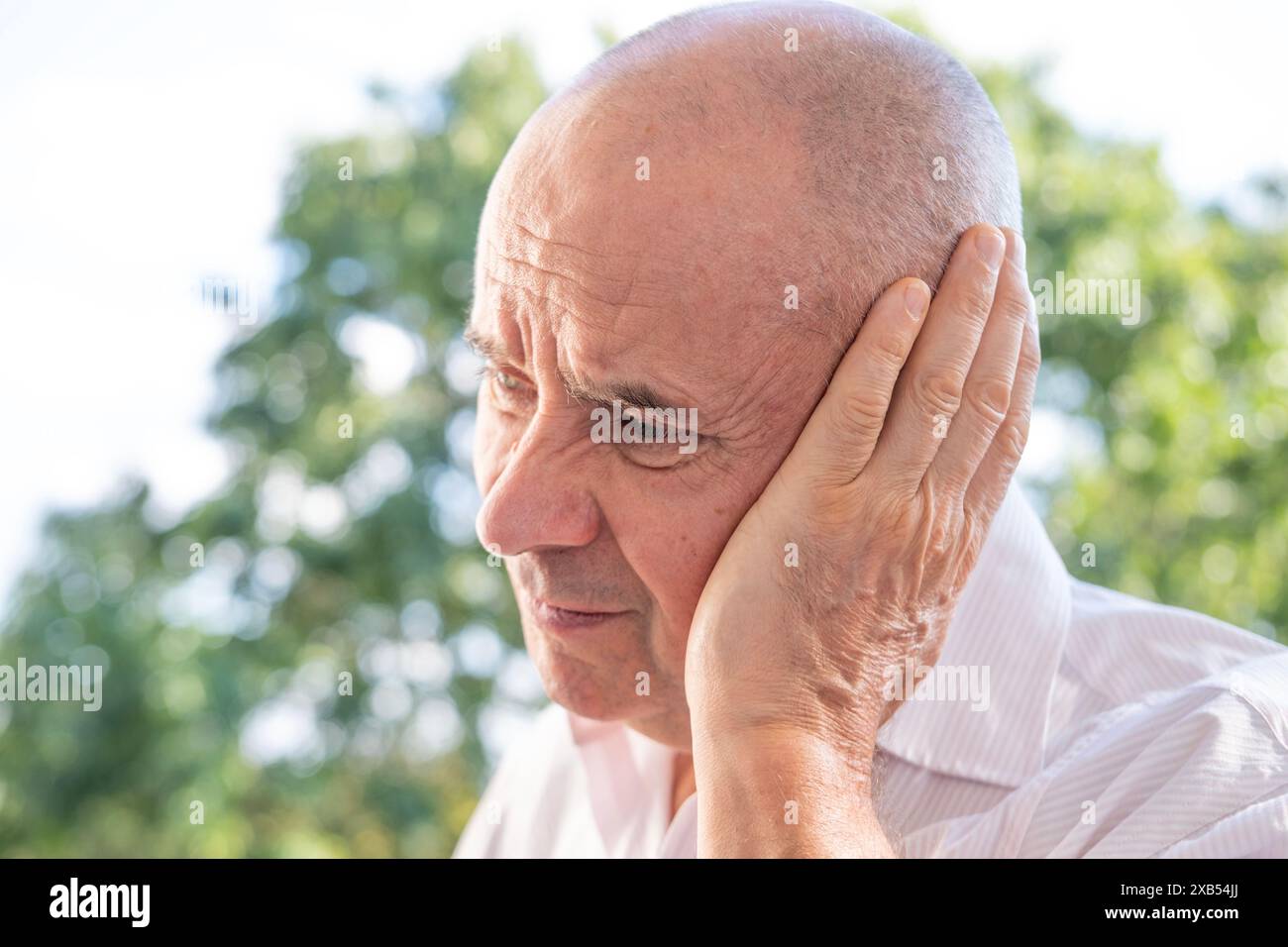 Anziano, uomo maturo 60-65 anni tiene all'orecchio, primo piano viso maschile con dolore di espressione facciale, squillo nelle orecchie, tinnito, infiammazione di mi Foto Stock
