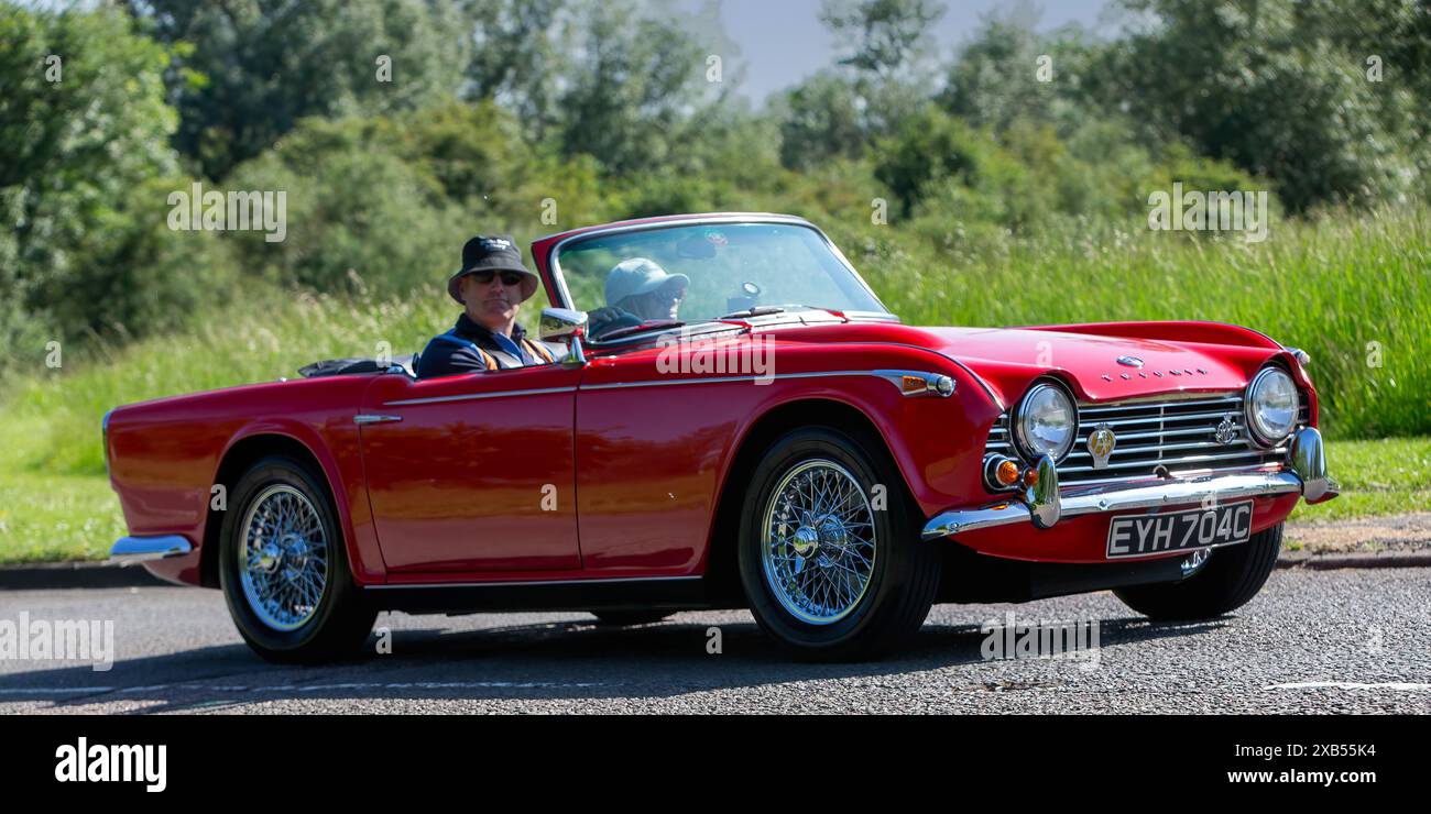 Stony Stratford, Regno Unito - 2 giugno 2024: 1965 auto sportiva britannica classica Triumph TR4 rossa su una strada di campagna britannica Foto Stock