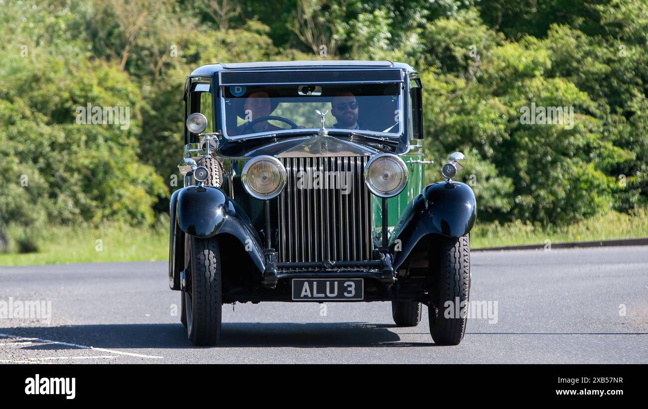 Stony Stratford, Regno Unito - 2 giugno 2024: 1933 auto d'epoca Rolls Royce verde che guida su una strada di campagna britannica Foto Stock