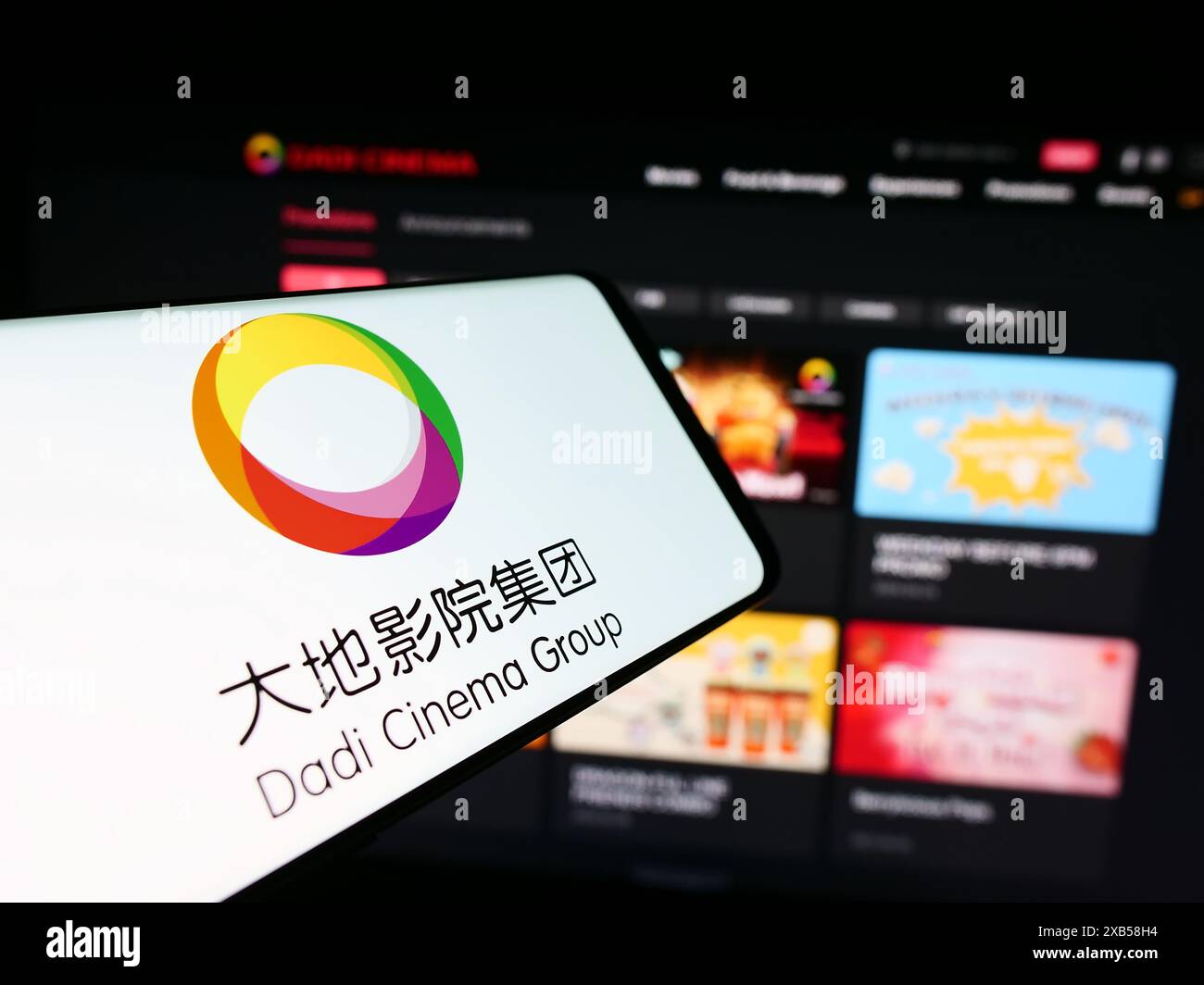 Cellpone con il logo della società asiatica di intrattenimento dadi Cinema di fronte al sito web aziendale. Messa a fuoco al centro del display del telefono. Foto Stock