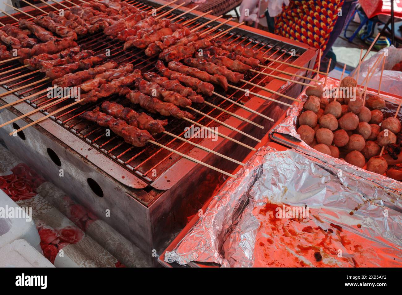 varie carni di maiale spiedate e polpette grigliate in un mercato di street food. Foto Stock