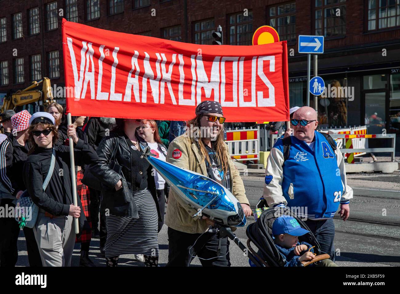 Vallankumous. I sostenitori di sinistra che portano la bandiera rossa a maggio marciano su Siltasaarenkatu nel distretto Hakaniemi di Helsinki, Finlandia. Foto Stock