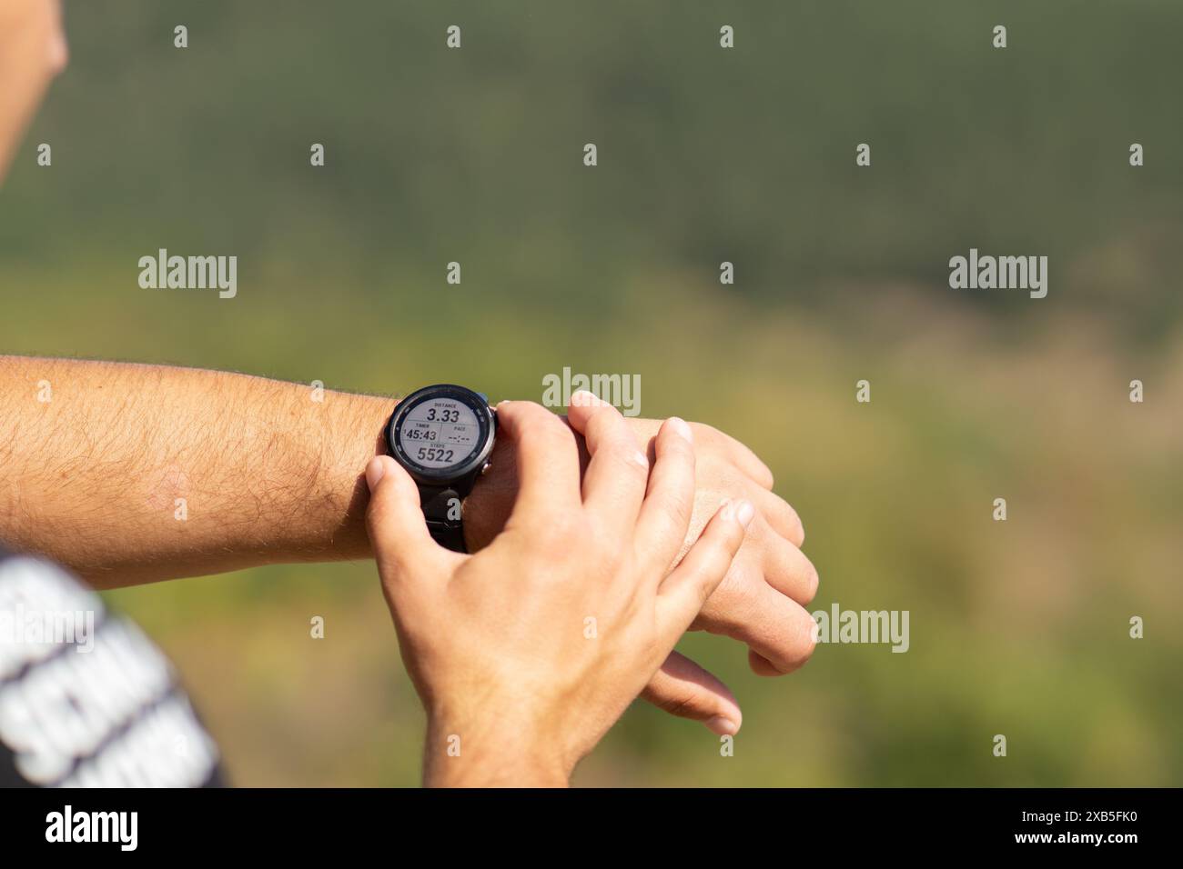 Runner sul sentiero della foresta di montagna controllare guardando lo sport guarda lo smartwatch cross country runner che controlla le prestazioni distanza battito cardiaco Foto Stock