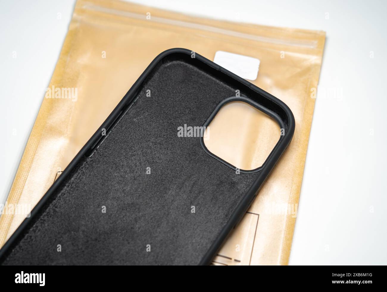 Custodia protettiva in silicone per iPhone 15 su una cover marrone. Sfondo bianco. Foto Stock