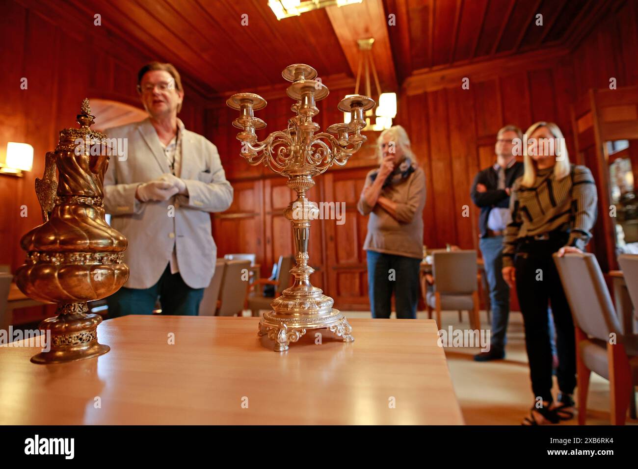 10 giugno 2024, Sassonia-Anhalt, Wernigerode: Il direttore del museo Christian Juranek (l.) mostra le ultime acquisizioni al castello di Wernigerode. Questi includono un decanter di vino del 1912, che il maestro costruttore Carl Frühling ricevette come regalo di addio dal principe Christian Ernst zu Stolberg-Wernigerode quando si ritirò, e un lampadario d'argento da Carl Frühling e sua moglie dal 1891. Gli oggetti furono acquisiti attraverso un contatto con i discendenti di Carl Frühling. Esse saranno esposte nella mostra permanente nel prossimo futuro. Nel castello sono attualmente in corso estesi lavori di costruzione. Il Foto Stock