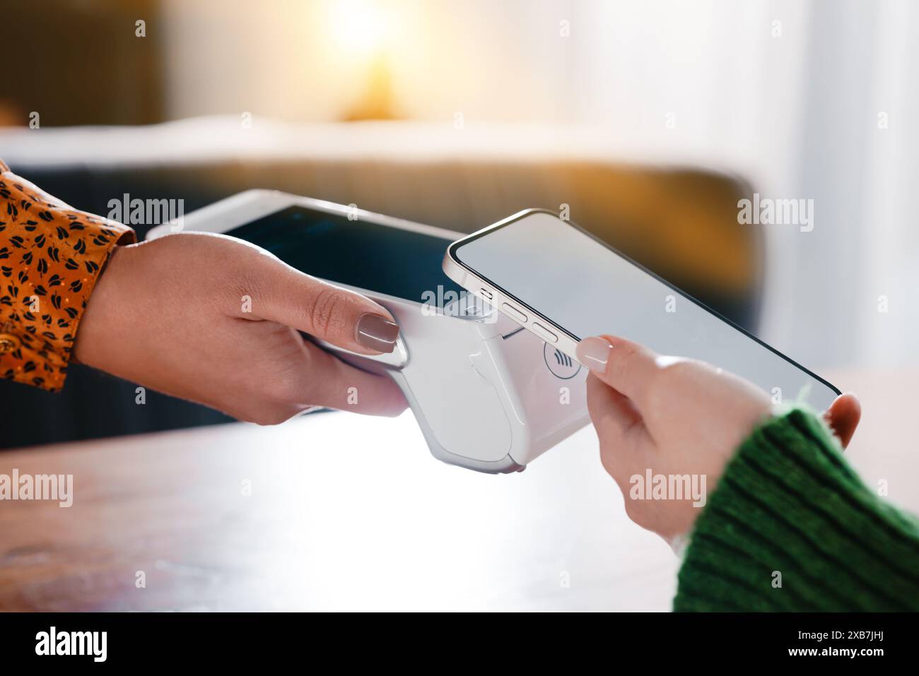 Mani impegnate nel pagamento senza contatto con smartphone e terminali, mostrando la moderna tecnologia di e-commerce Foto Stock