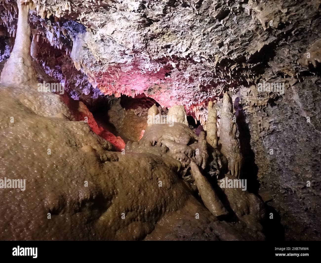 Una piccola grotta illuminata da una luce rosa con gocce di vernice rossa Foto Stock