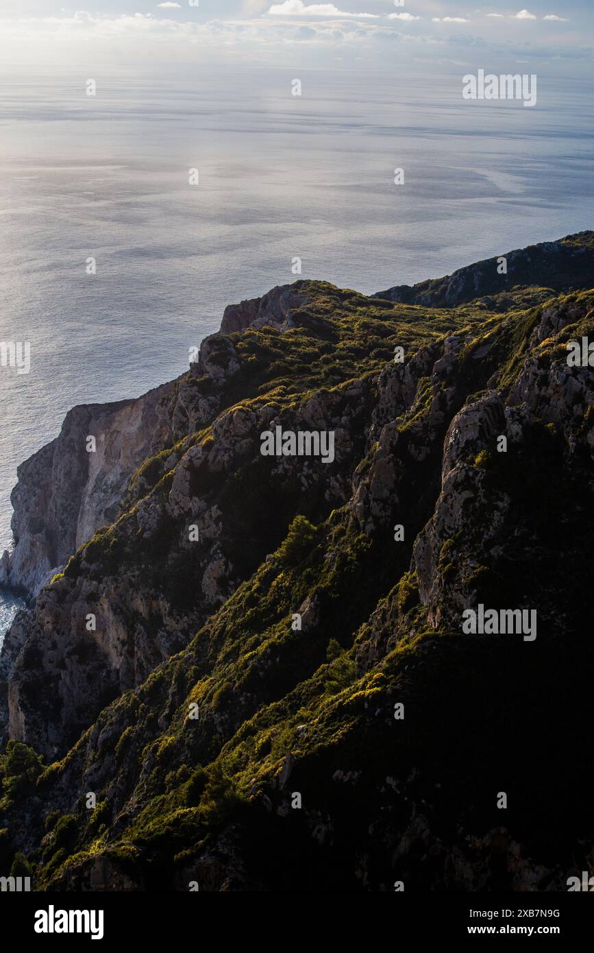 Alte cime di montagna ricoperte di foreste vicino a un ampio oceano Foto Stock