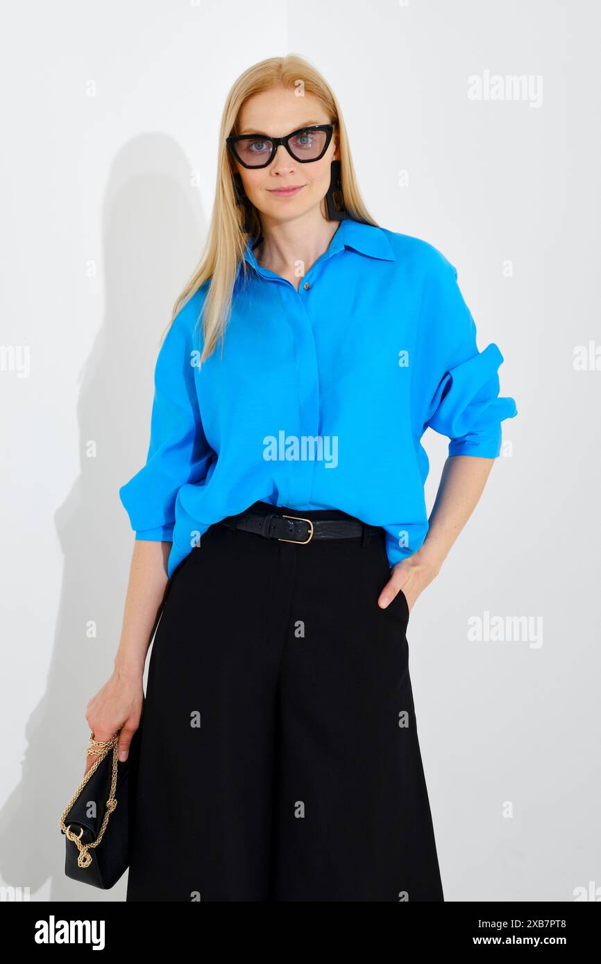 Primo piano medio di una donna carina che indossa una camicia blu con bottoni e una maxi gonna su sfondo bianco Foto Stock