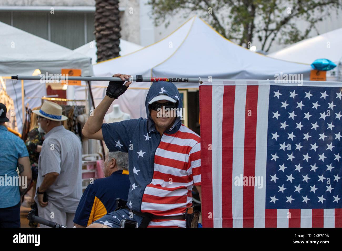 Un uomo che indossa un cappello alza una bandiera a Coral Gables, Florida, Stati Uniti Foto Stock