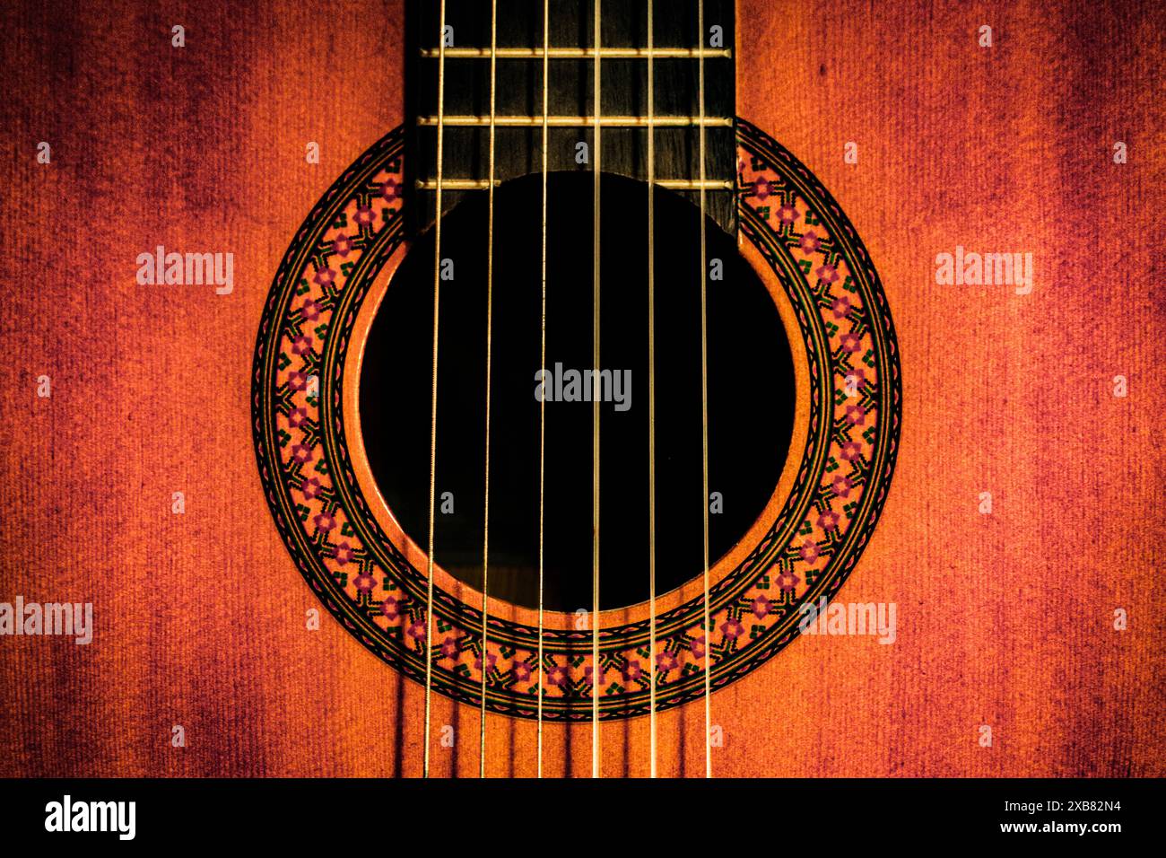 Uno scatto ravvicinato della soundboard di una chitarra in tonalità rossastre Foto Stock