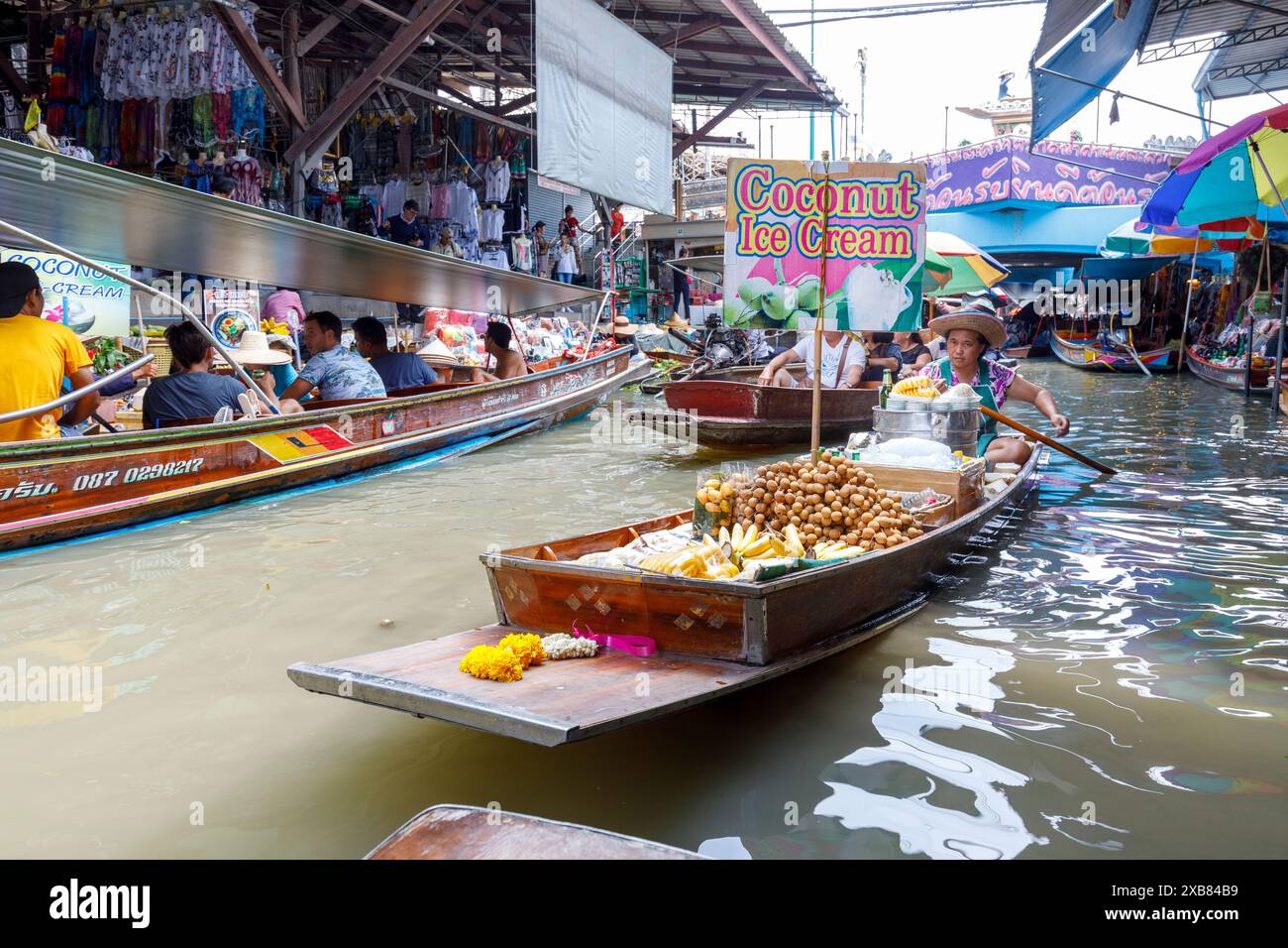 Vendita di gelato al cocco dalla barca al mercato galleggiante di Tha Kha, Thailandia Foto Stock