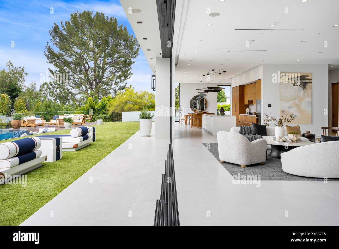 Un'area soggiorno aperta si collega perfettamente al cortile con mobili eleganti e una piscina Foto Stock