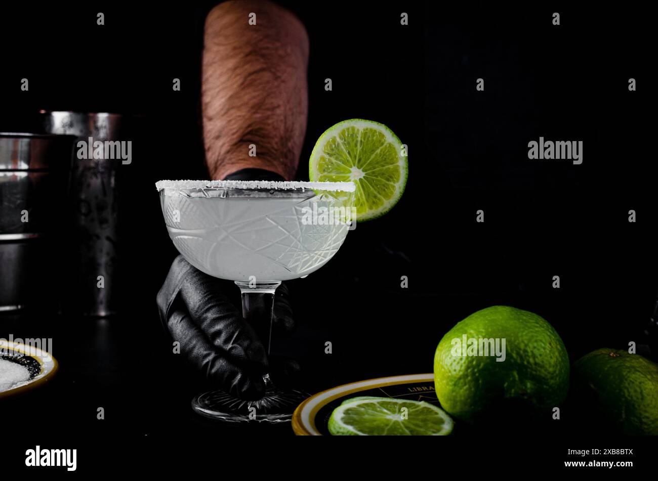 Barman che serve un margarita guarnito con fette di lime Foto Stock