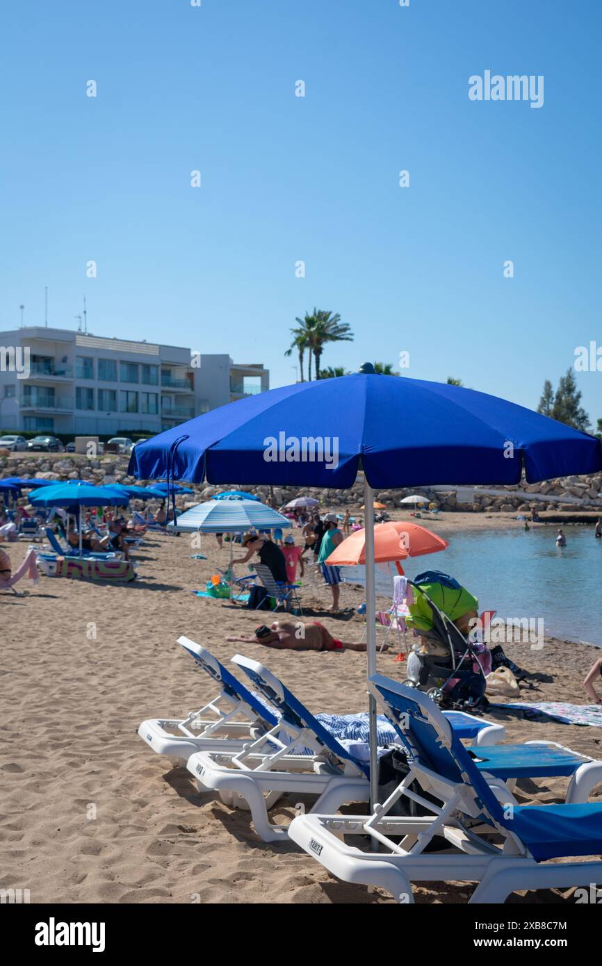 Un gruppo di persone che si rilassano e si prendono il sole sulla spiaggia di sabbia Foto Stock