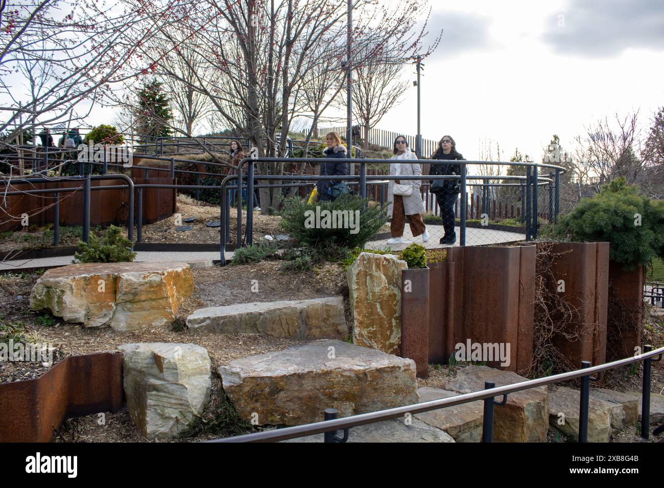 Un gruppo di individui in piedi vicino a massi sul terreno in un parco di New York, Stati Uniti Foto Stock