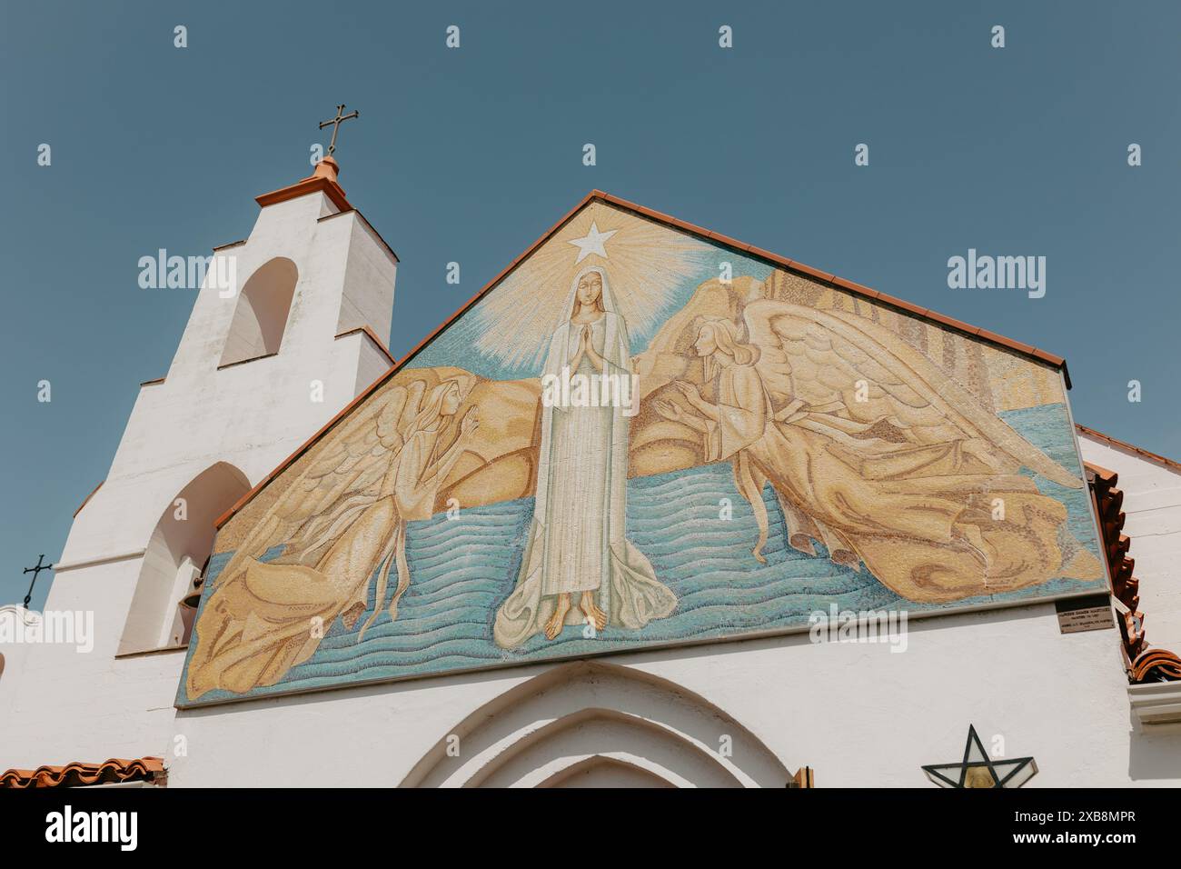 Un'icona religiosa femminile con due angeli in un ambiente celeste, raffigurata sulla facciata di una chiesa Foto Stock