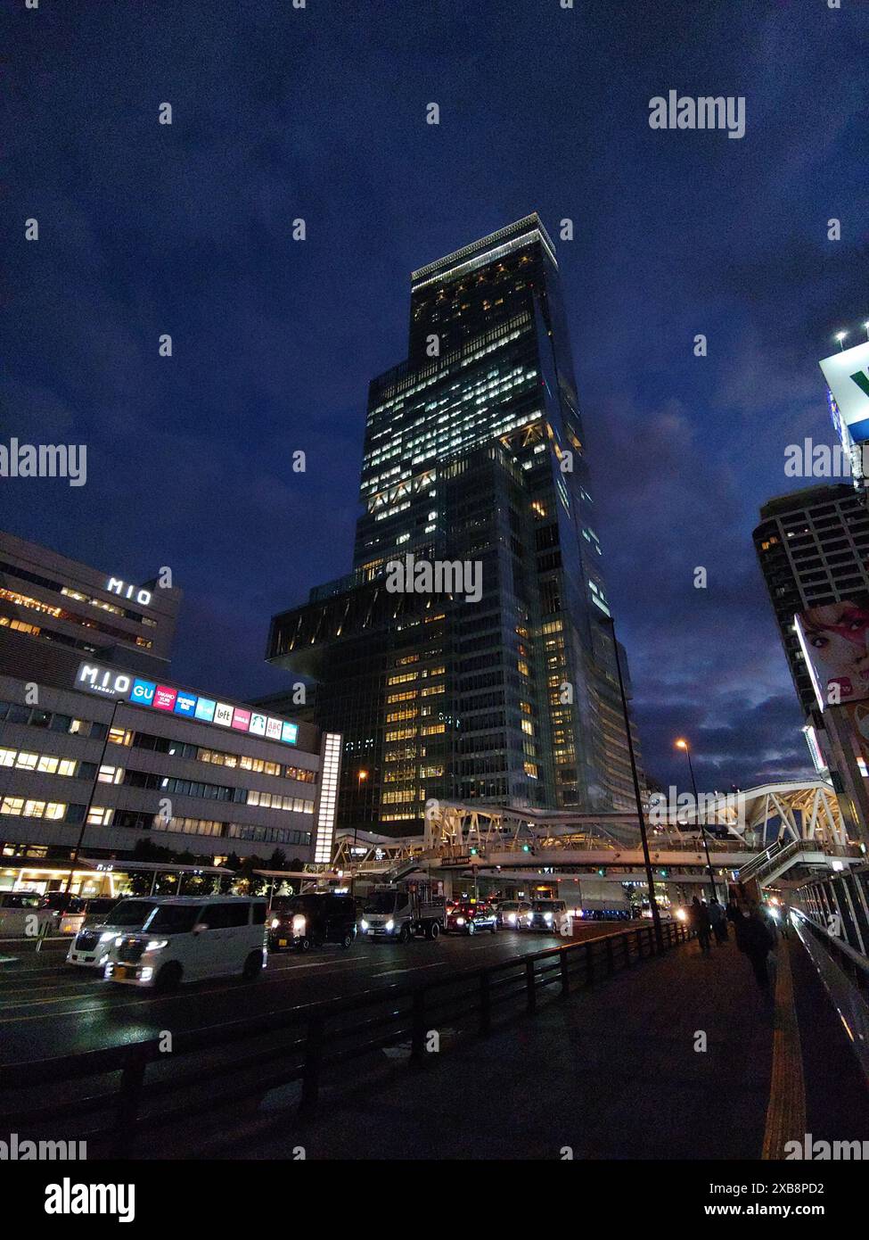 Una vivace strada urbana di notte con edifici alti e auto parcheggiate Foto Stock