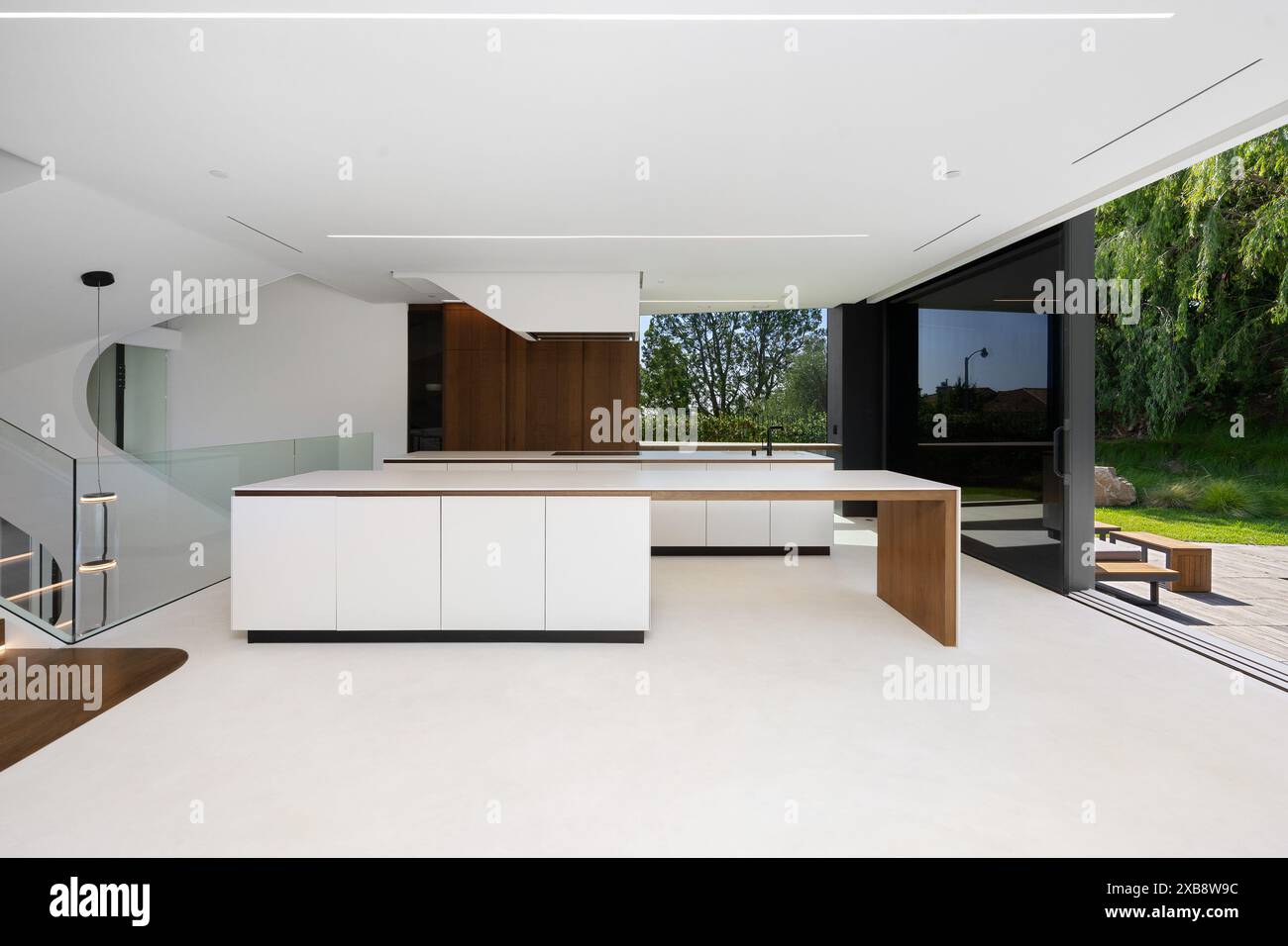 Cucina open space con piano bianco, ripiani in legno e porte Foto Stock