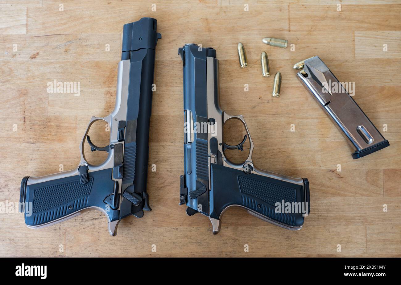 Un paio di classiche pistole polizia da 9 mm su un tavolo di legno. Uno con freno a bocca e compensatore e l'altro senza. Foto Stock