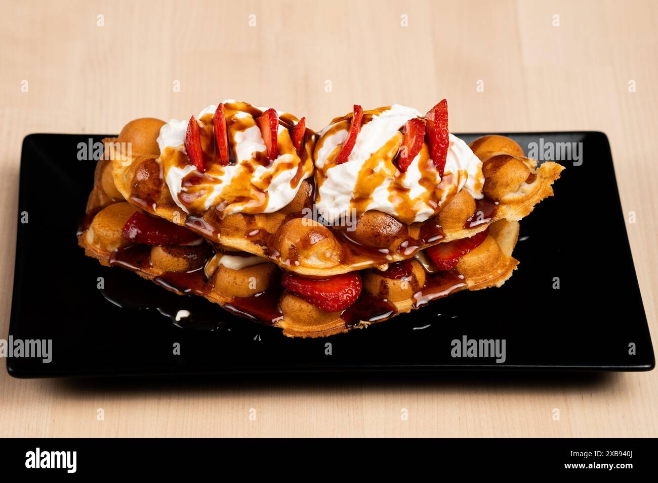 Un delizioso dessert con waffle, fragole e sciroppo Foto Stock