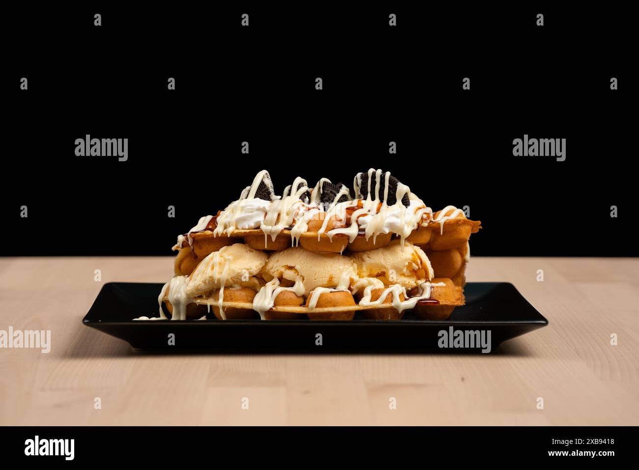 Un dessert gelato avvolto in un waffle su un piatto nero Foto Stock