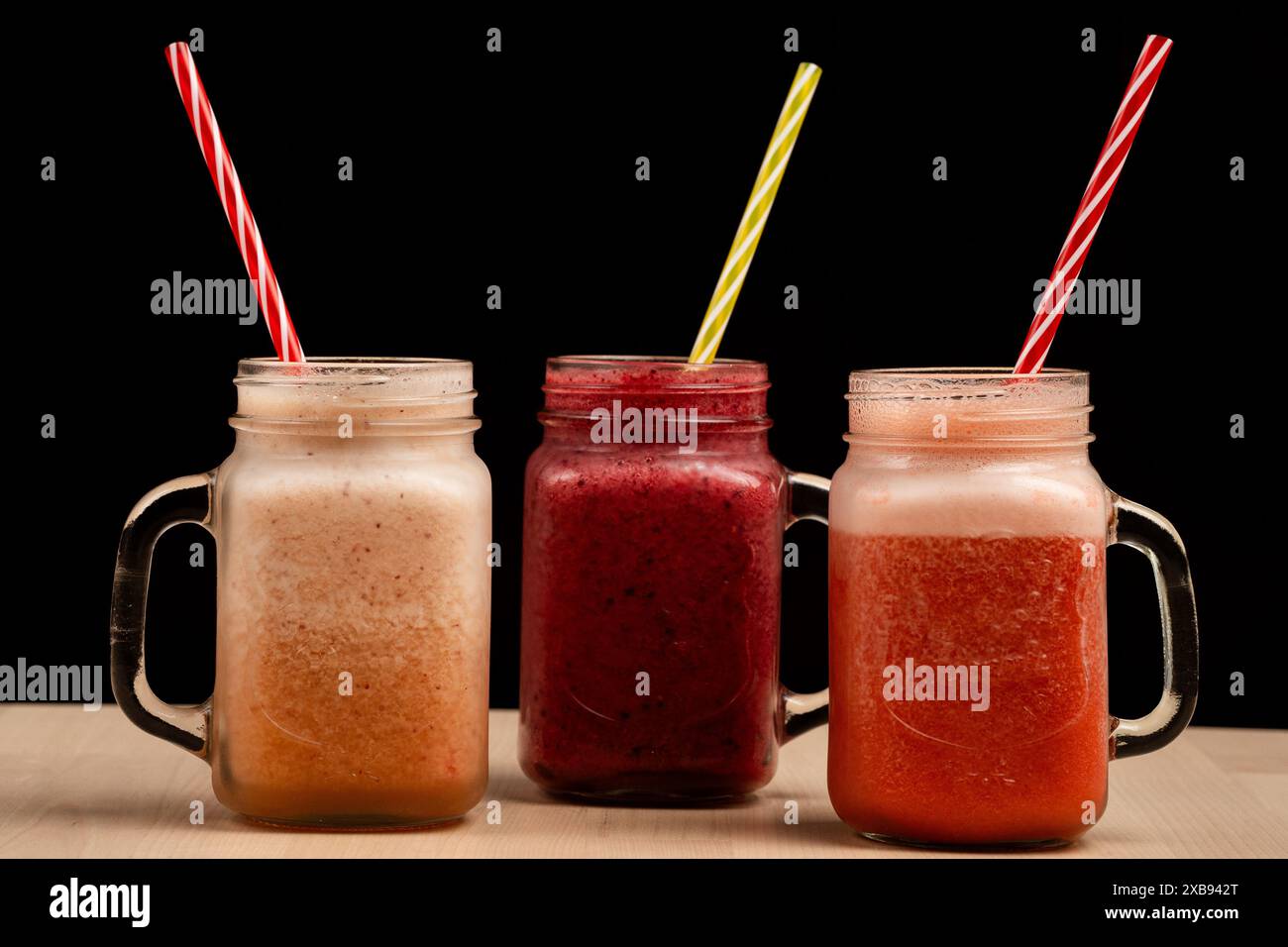 Tre bevande in tonalità di rosso con cannucce Foto Stock