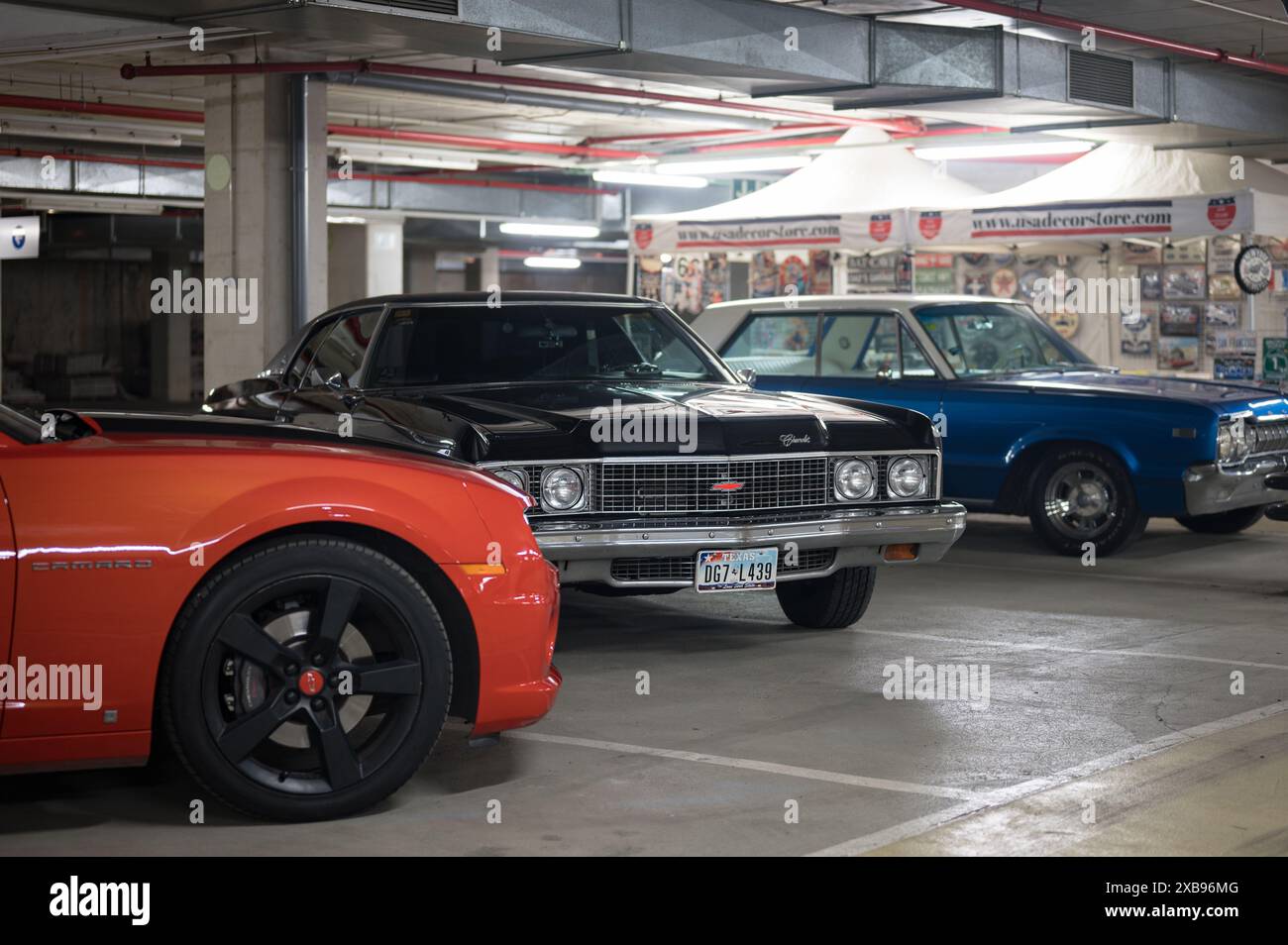 Parcheggio sotterraneo, una Chevrolet Camaro rossa e due splendidi classici, la Chevrolet Impala nera di quinta generazione e una Dodge Polara blu Foto Stock