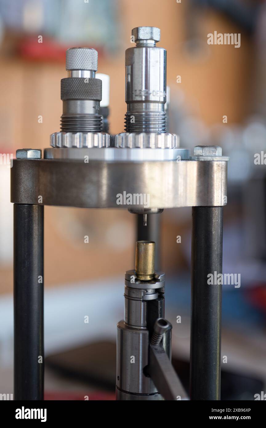 Dettaglio del processo di decapping e ridimensionamento di un contenitore da 9 mm nella pressa di ricarica. Foto Stock