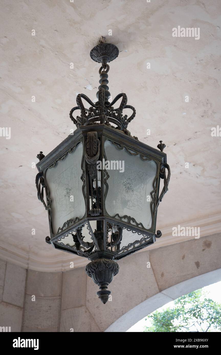 lampada ornata in ferro battuto appesa al soffitto. E' di forma quadrata e si trova in un vecchio edificio dall'architettura di Barcellona. Foto Stock
