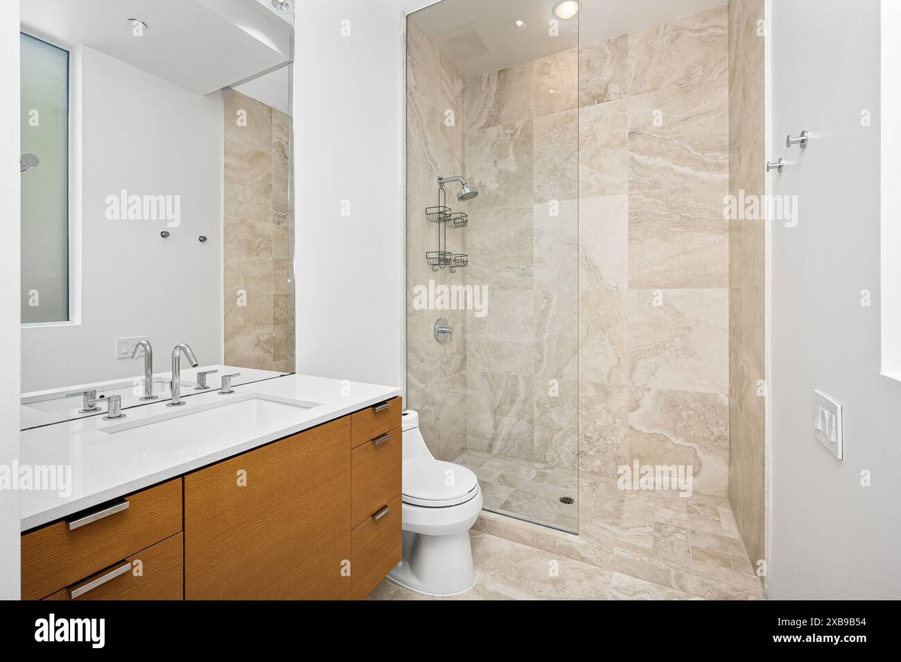 Un lussuoso bagno in marmo con elegante lavandino bianco, specchio e WC Foto Stock