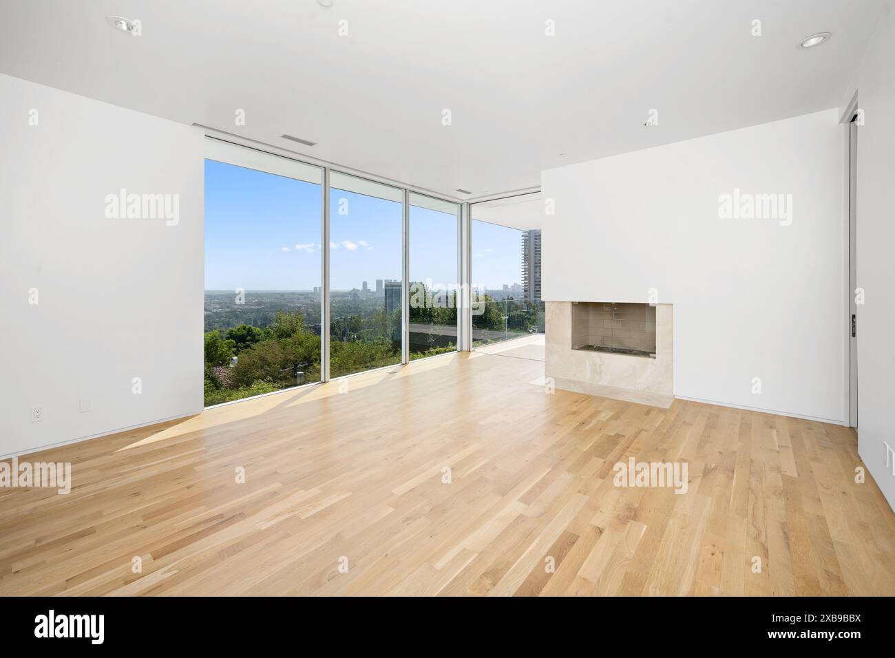 Uno spazioso soggiorno con porte di vetro a tutta lunghezza e pavimenti in legno Foto Stock