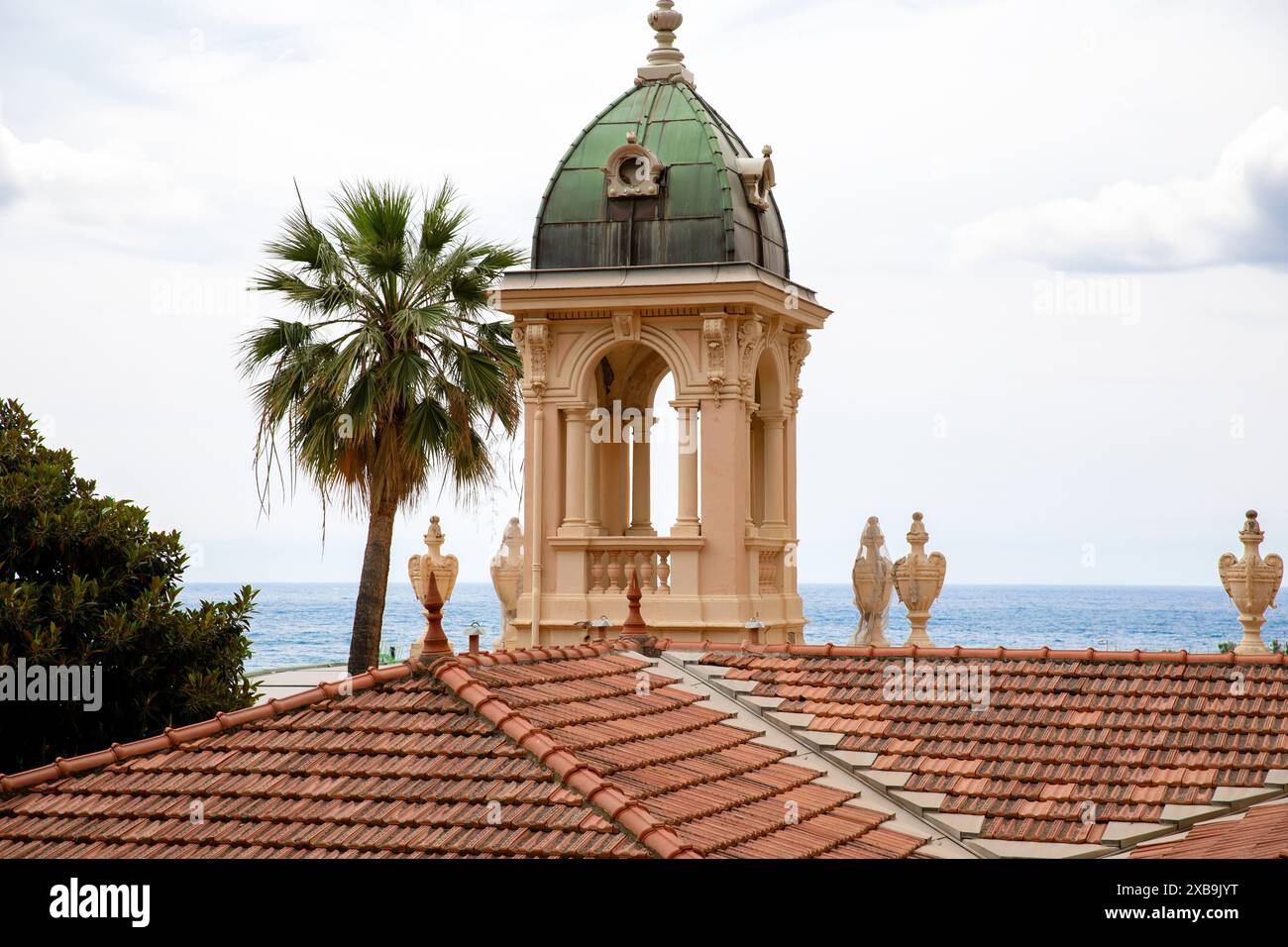 Una splendida vista di una torre in stile mediterraneo con una cupola in rame e dettagli decorati, sullo sfondo del mare di Monaco. La scena è comp Foto Stock