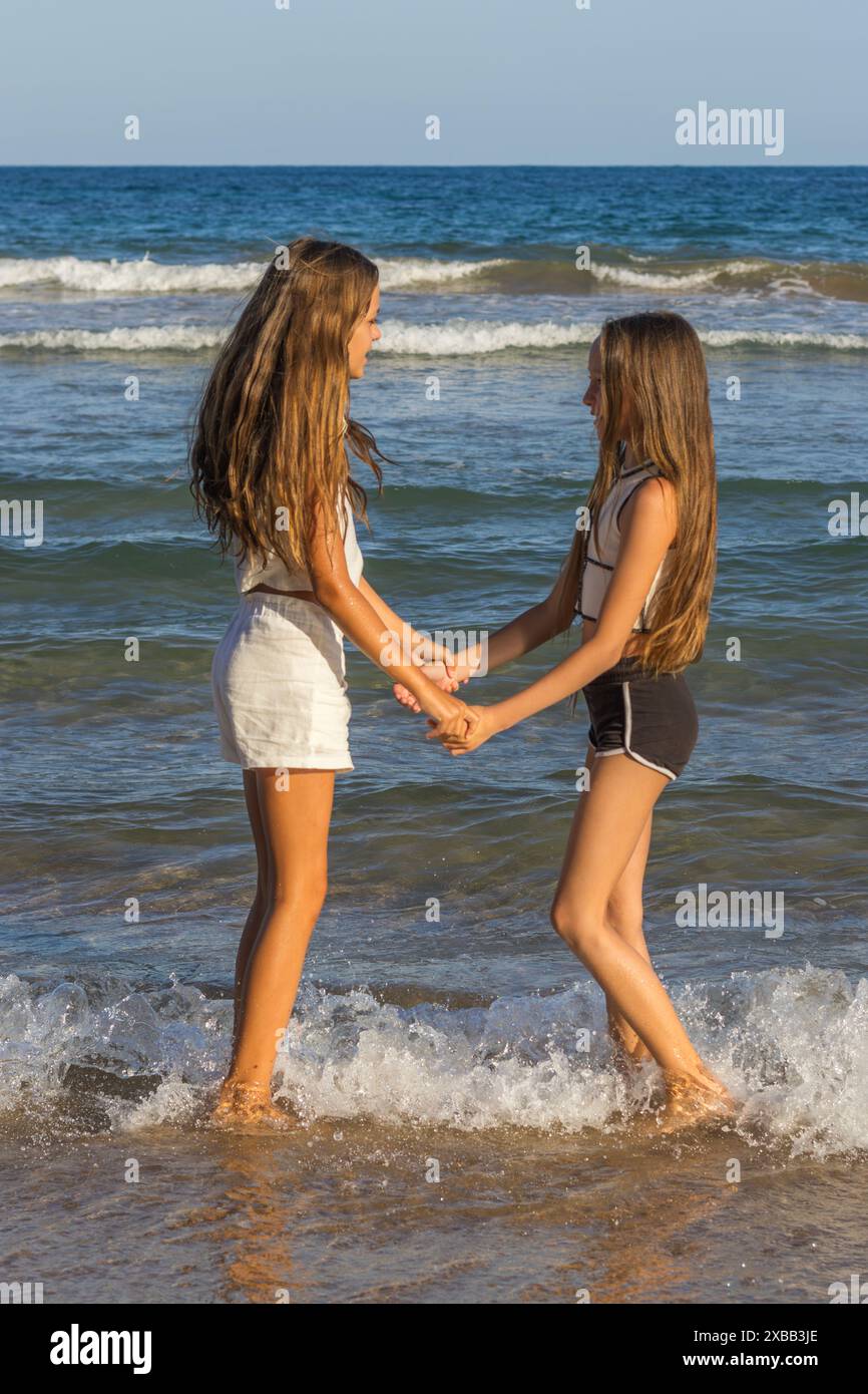 Questa immagine cattura meravigliosamente i momenti dorati di due splendide sorelle gemelle con lunghi capelli biondi e occhi verdi Foto Stock