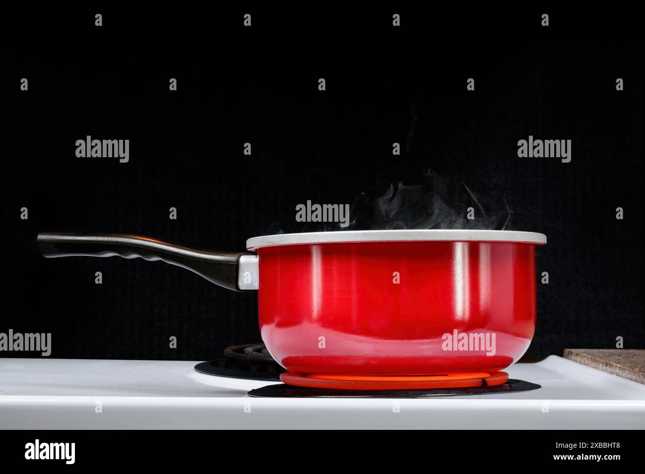 Shot orizzontale di qualcosa che fuma caldo in una pentola rossa con sfondo nero. Copia spazio. Foto Stock