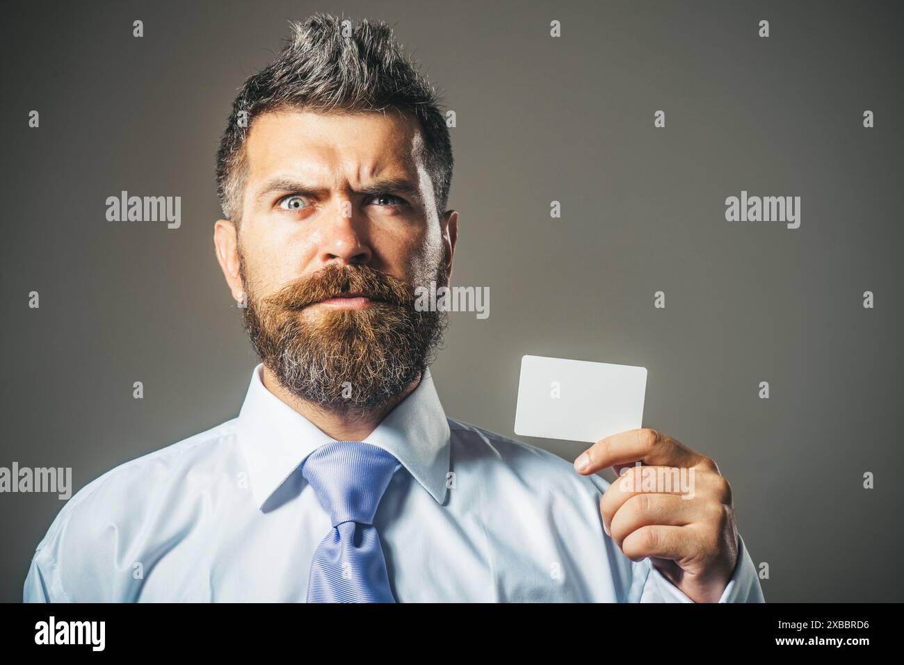 Uomo barbuto sorpreso con un mockup vuoto biglietto da visita vuoto. Bell'uomo d'affari, finanziere, banchiere che mostra carta di credito o debito. Finanza, pa Foto Stock