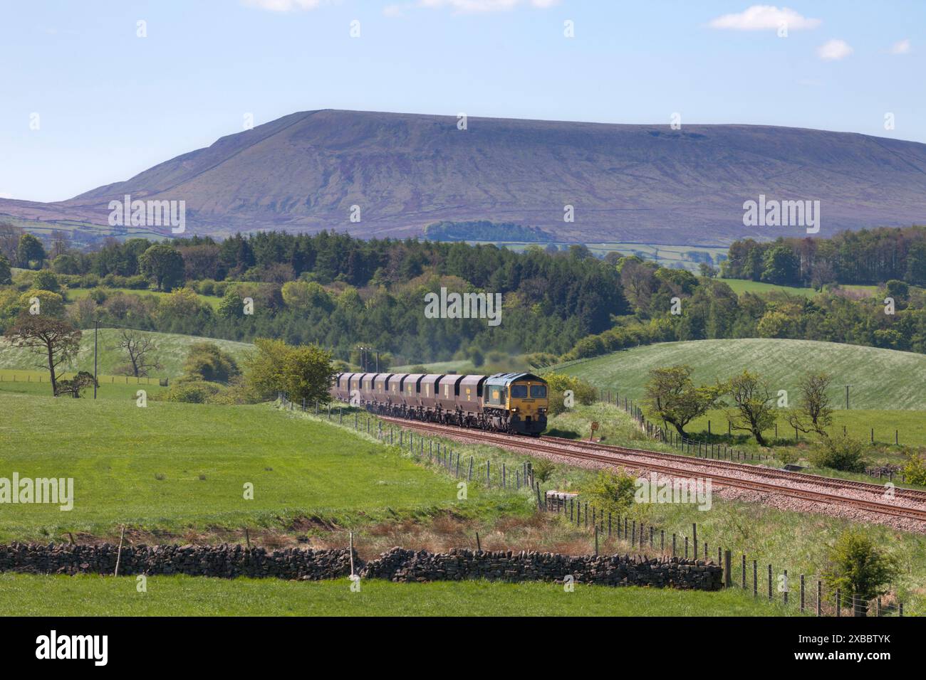 Locomotiva Freightliner classe 66 66520 che trasporta un treno merci a carbone "Merry Go Round" sulla ferrovia Blackburn-Hellifield, Pendle Hill è dietro Foto Stock