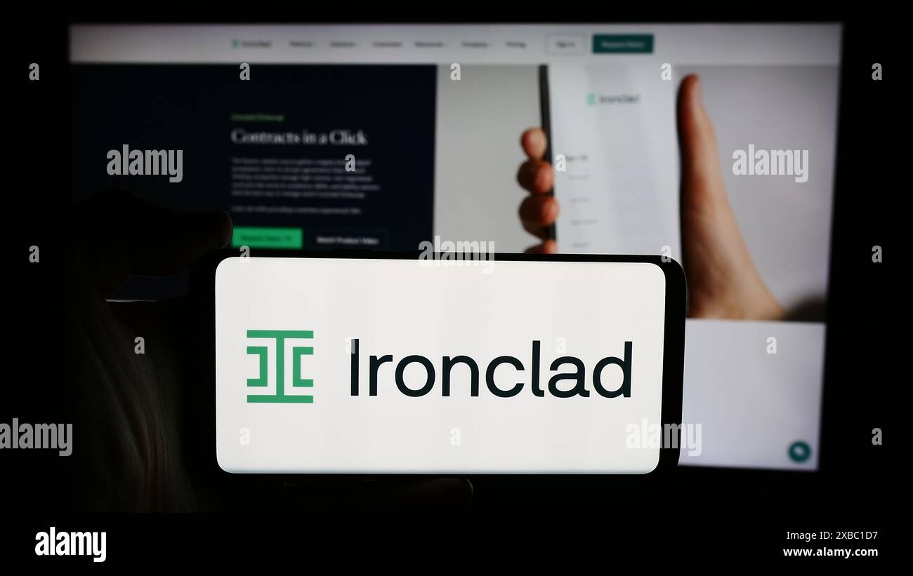 Persona che detiene un cellulare con il logo della società statunitense Ironclad Inc. Di fronte alla pagina Web aziendale. Mettere a fuoco il display del telefono. Foto Stock