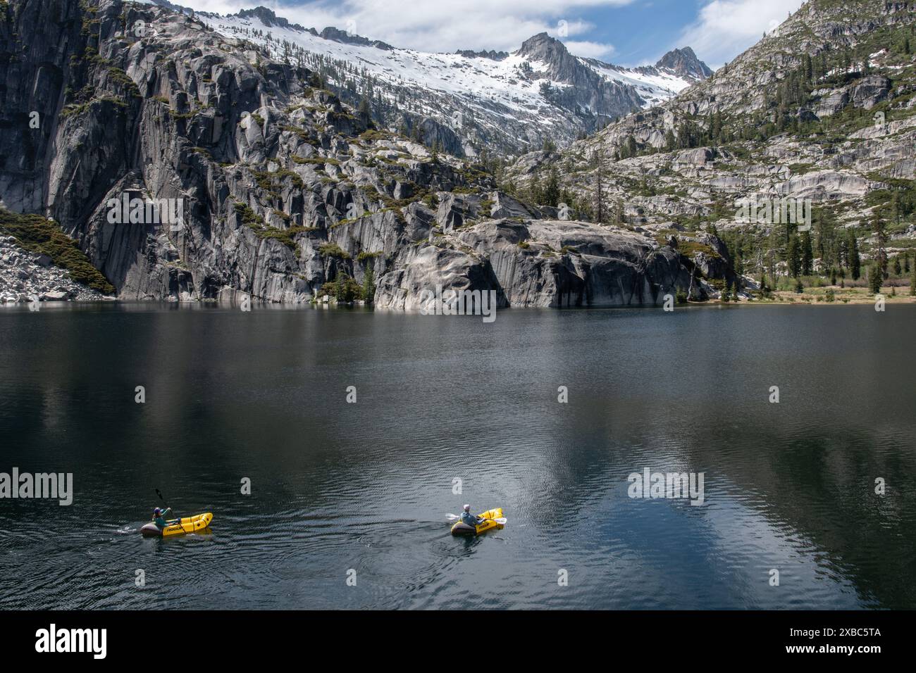 Il bellissimo paesaggio montano e il lago ad alta quota nella natura selvaggia delle Alpi della Trinità di Shasta. Un paio di kayak distanti pagaiano sul lago. Foto Stock