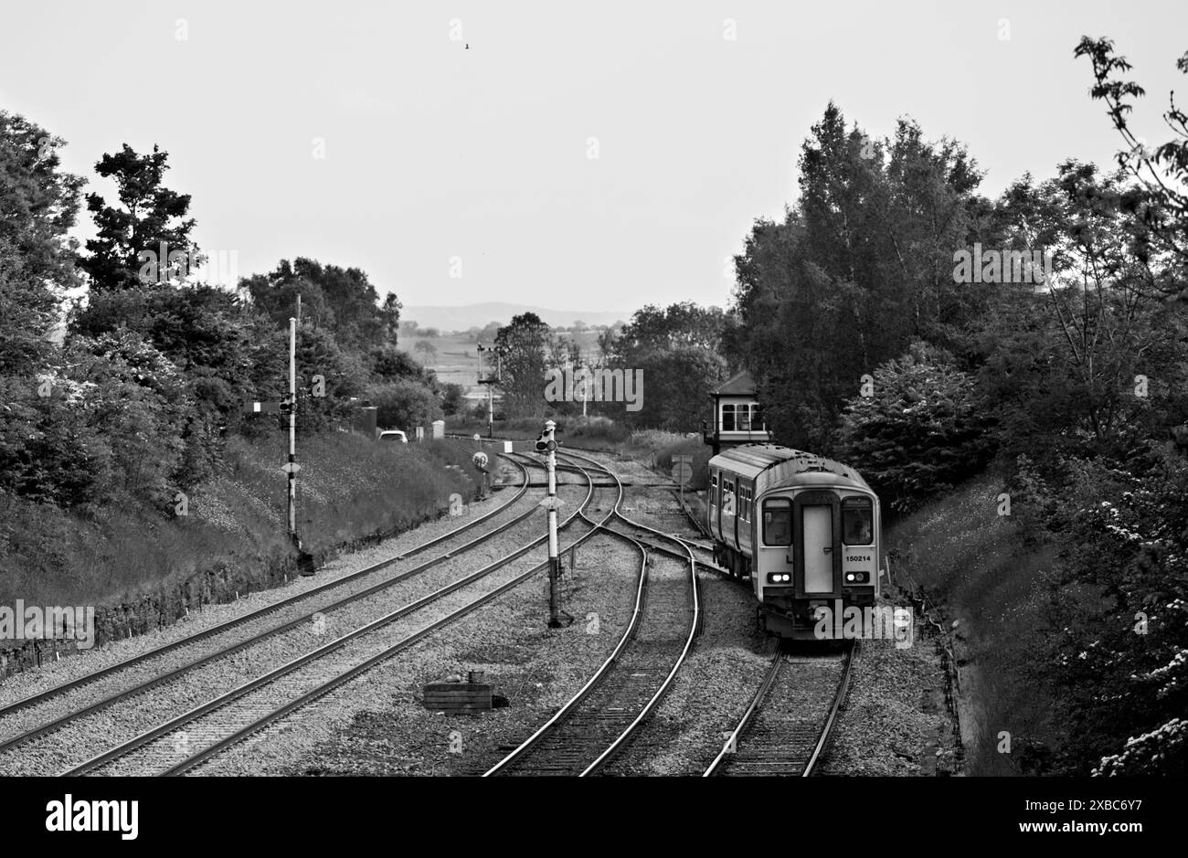 Treno DMU classe 150 Northern Rail 150214 che passa i segnali a semaforo all'incrocio Settle e si dirige verso la piccola linea nord-occidentale Foto Stock