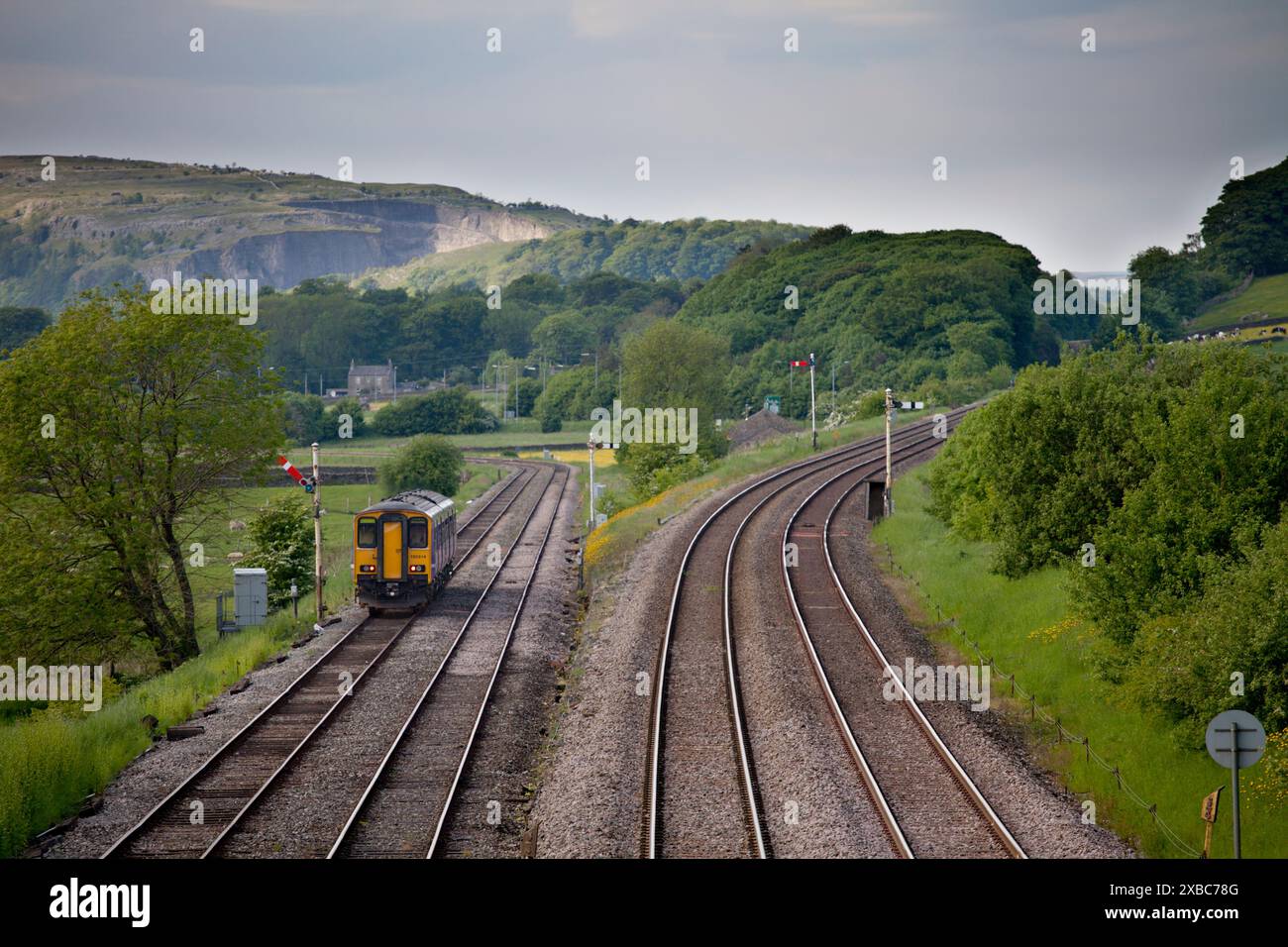 Treno DMU classe 150 Northern Rail 150214 che passa i segnali a semaforo all'incrocio Settle e si dirige verso la piccola linea nord-occidentale Foto Stock