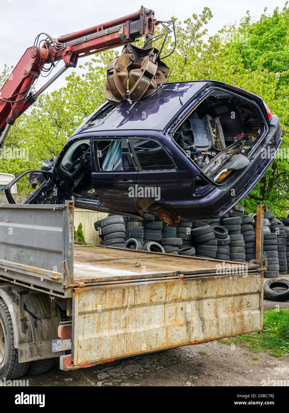 Il processo di caricamento di un relitto di un'auto abbandonata mediante un caricatore idraulico montato su un autocarro trainante, un'auto che viene smaltita, al sito di riciclaggio Foto Stock