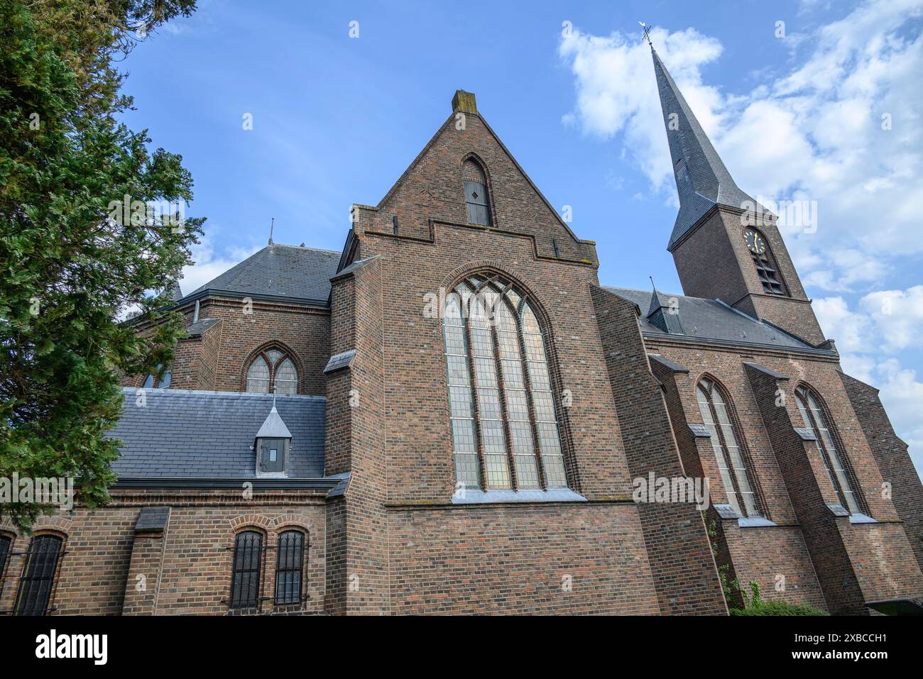 Primo piano di una grande chiesa in mattoni con magnifiche finestre sotto un cielo leggermente nuvoloso, Bredevoort, gelderlande, paesi bassi Foto Stock