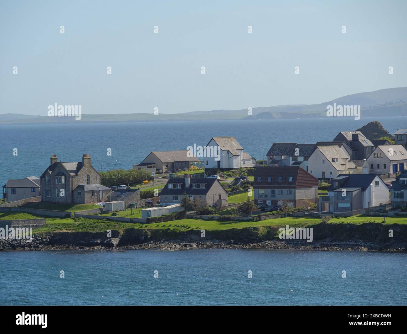 Costa con diverse case e verdi colline direttamente sul mare, lerwick, shetlands, scozia, gran bretagna Foto Stock